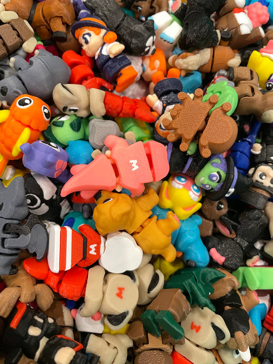 A dense pile of small, colorful plastic toy figures and animal characters filling the frame. Wigglitz jointed 3d critters.
